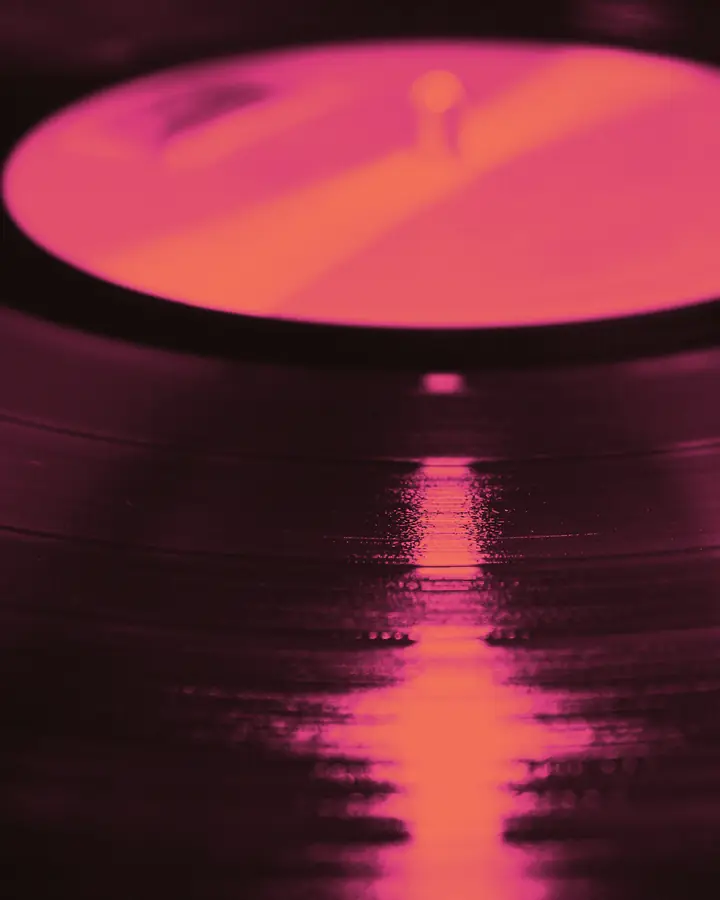 Un disco in vinile sul piatto, in duotone magenta.