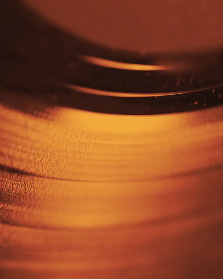 Il solco di un disco in vinile, in macro, in duotone ambra.